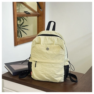 Close-up of cream yellow nylon backpack with wrinkled texture and round metal logo