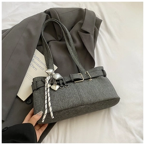 Detail of grey woolen bucket bag featuring silver buckles and decorative heart charms