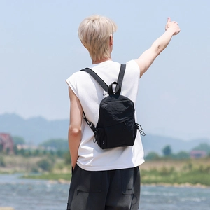 Close-up of a black nylon backpack featuring a white bird logo and pleated design details