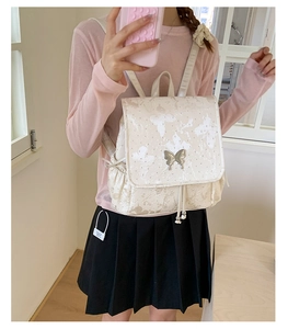 Detailed view of silver butterfly metal buckle on cream white faux leather backpack