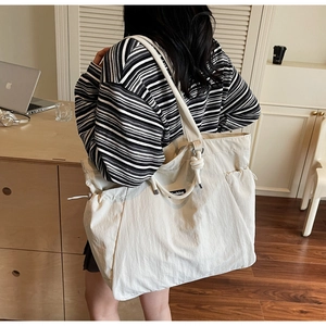 Detail of off-white nylon tote bag with drawstring pocket and woven rope handle accents