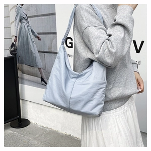 Detail of light blue nylon tote bag showing side pocket and wrinkled texture fabric