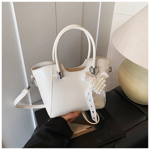 Close-up of white bucket bag featuring pearl heart charm and lace bow detail