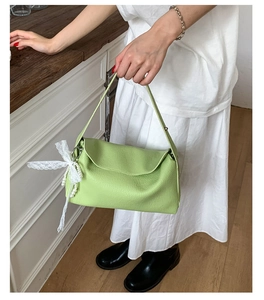Detail of fresh green dumpling bag with white lace bow and elegant pearl chain handle