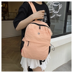 Detail view of peach casual backpack featuring drawstring mesh side pockets and front zipper