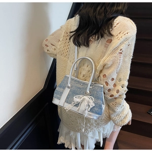 Detail der hellblauen Denim-Beuteltasche mit Spitzenschleife und Silberbesatz