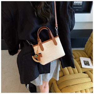 Detail of canvas handbag featuring brown leather trim and a horse-shaped leather charm