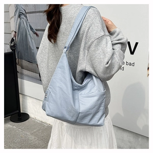 Light blue nylon tote bag worn by a model, showing large capacity and side pockets