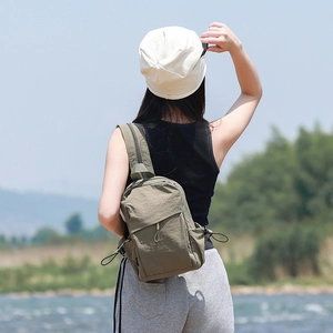 Army green nylon crossbody bag detail with multiple pockets in outdoor scenic setting