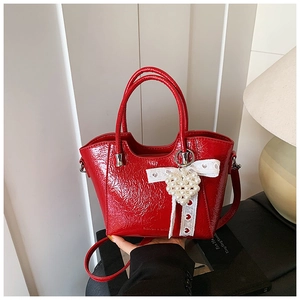 Detail of red patent leather bucket bag with lace trim and heart pearl pendant