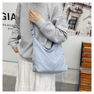 Detail of light blue nylon tote bag with textured surface and adjustable wide strap