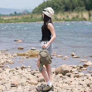 Olive green nylon backpack for hiking shown against a natural riverside landscape background