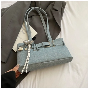 Detail of light blue denim texture shoulder bag with heart pendant and buckle accents