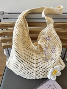 Beige Häkel-Einkaufstasche mit Blumenverzierung und lila Perlen auf Holzstuhl