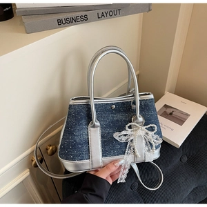 Detail der blauen Denim-Beuteltasche mit silbernen Griffen und Perlen-Schleifen-Anhänger