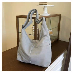 Detail of light gray nylon tote bag with textured surface on a wooden table