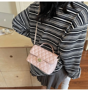 Detailed side view of pink quilted handbag with gold chain strap on model