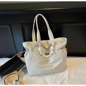Detail of off-white nylon tote bag showing textured fabric and braided rope handle