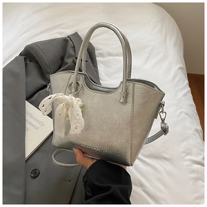 Detail of silver bucket bag featuring glossy PU texture and pearl bow charm accessory