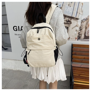 Close-up of off-white travel backpack with dual zippers and side mesh pockets