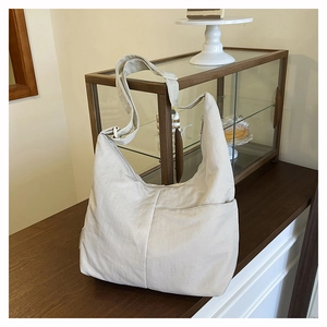 Macro detail of beige nylon hobo bag featuring an adjustable strap and large front pocket