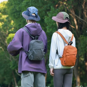 Outdoor backpacks in grey and orange shown in forest setting with high UV protection clothing