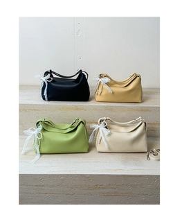 Detail view of four dumpling bags in black, yellow, green, and beige with lace bows