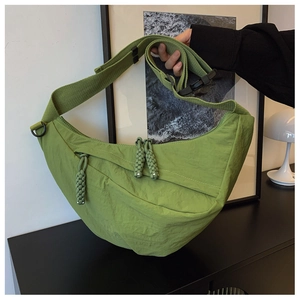 Dettaglio della borsa a mezzaluna verde con tracolla larga e trama in nylon fine