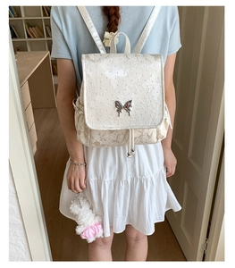 Détail du sac à dos blanc crème avec broderie papillon et boucle en métal élégante