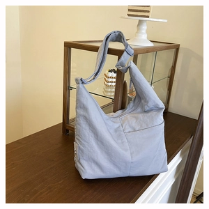 Detail of light blue nylon crescent bag showing adjustable strap and side zipper pocket