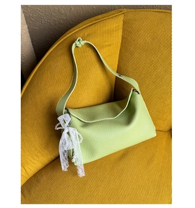 Detail of light green leather dumpling bag with lace bow and pearl pendant charm