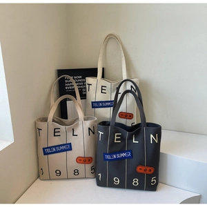 Close-up of canvas tote bags showing side patches and printed graphics in three colors