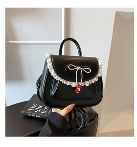 Dettaglio di zaino nero con pizzo bianco e perline rosse decorative sui fiocchi