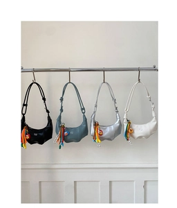 Detail of minimalist crescent shoulder bags in four colors with colorful ball charms