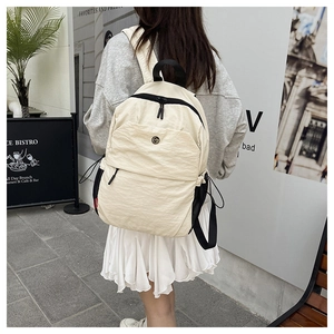 Detailed close-up of cream nylon backpack with pleated texture and utility side pockets