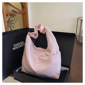Detail of pink nylon hobo bag featuring front pocket and adjustable shoulder strap