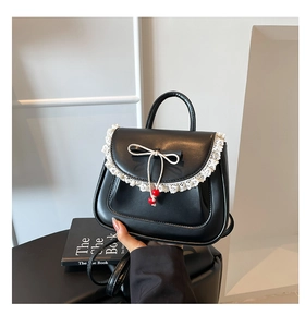 Dettaglio borsa nera in ecopelle con bordo in pizzo bianco e fiocco con perline rosse