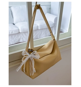 Detail of yellow pebbled leather handbag featuring white lace and pearl bow charms