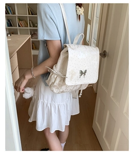 Close-up of cream butterfly backpack with metallic hardware buckle and floral pattern