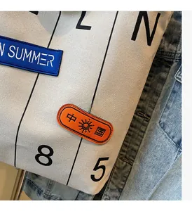 Detail of canvas tote bag featuring vintage embroidery patches and printed letters