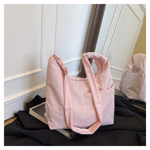 Detail view of pink nylon tote bag featuring a knotted shoulder strap and side pocket