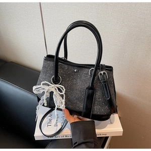 Nahaufnahme der schwarz-grauen Tweed-Tasche mit Perlen-Spitzen-Bogen und silbernen Details