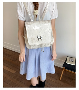 Detail of butterfly embroidery on cream backpack with decorative silver butterfly clasp