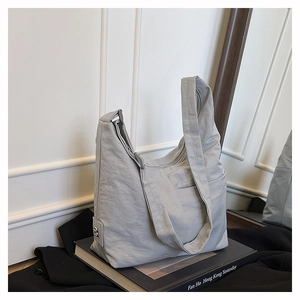 Detail view of the light grey nylon tote bag with crinkled texture and metal brand tag