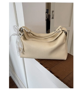 Detail of cream beige lychee texture leather bag with pearl and lace bow charm