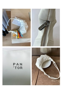 Detail of white leather croissant bag with rainbow braided rope and donut charm