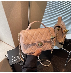 Detailed shot of pink quilted crossbody bag with gold metal chain and ball charm