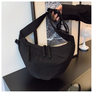 Dettaglio della borsa a mezzaluna in nylon nero con doppie cerniere e tracolla larga