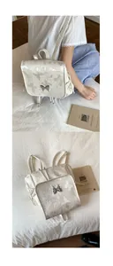 Détail d'un sac à dos crème avec broderie papillon et boucle en métal argenté élégante