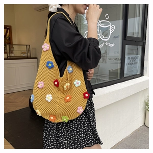 Détail d'un sac cabas en tricot jaune avec fleurs au crochet colorées en gros plan